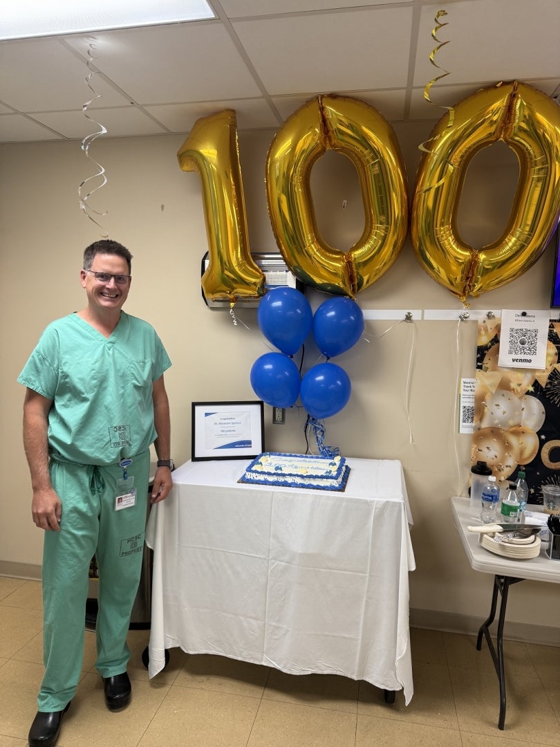 Dr. Spence and the numbers 100 in gold balloons